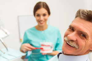 MalePatientSmilingwDentistwMouthModel